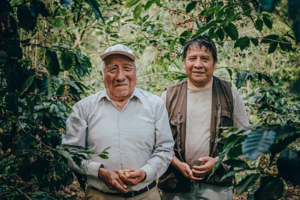 Dos agricultores cooperativistas conversando en una plantación de café